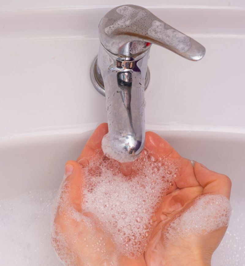 Person washing hands under running faucet