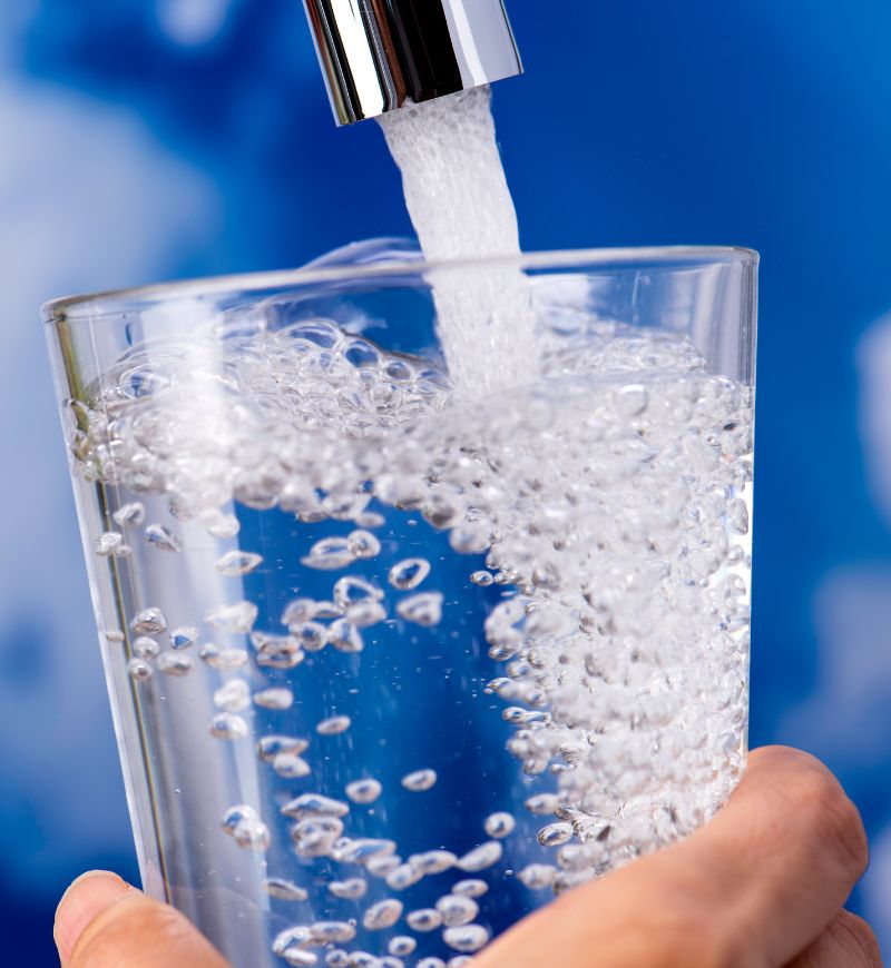 Water flowing from faucet into clear glass