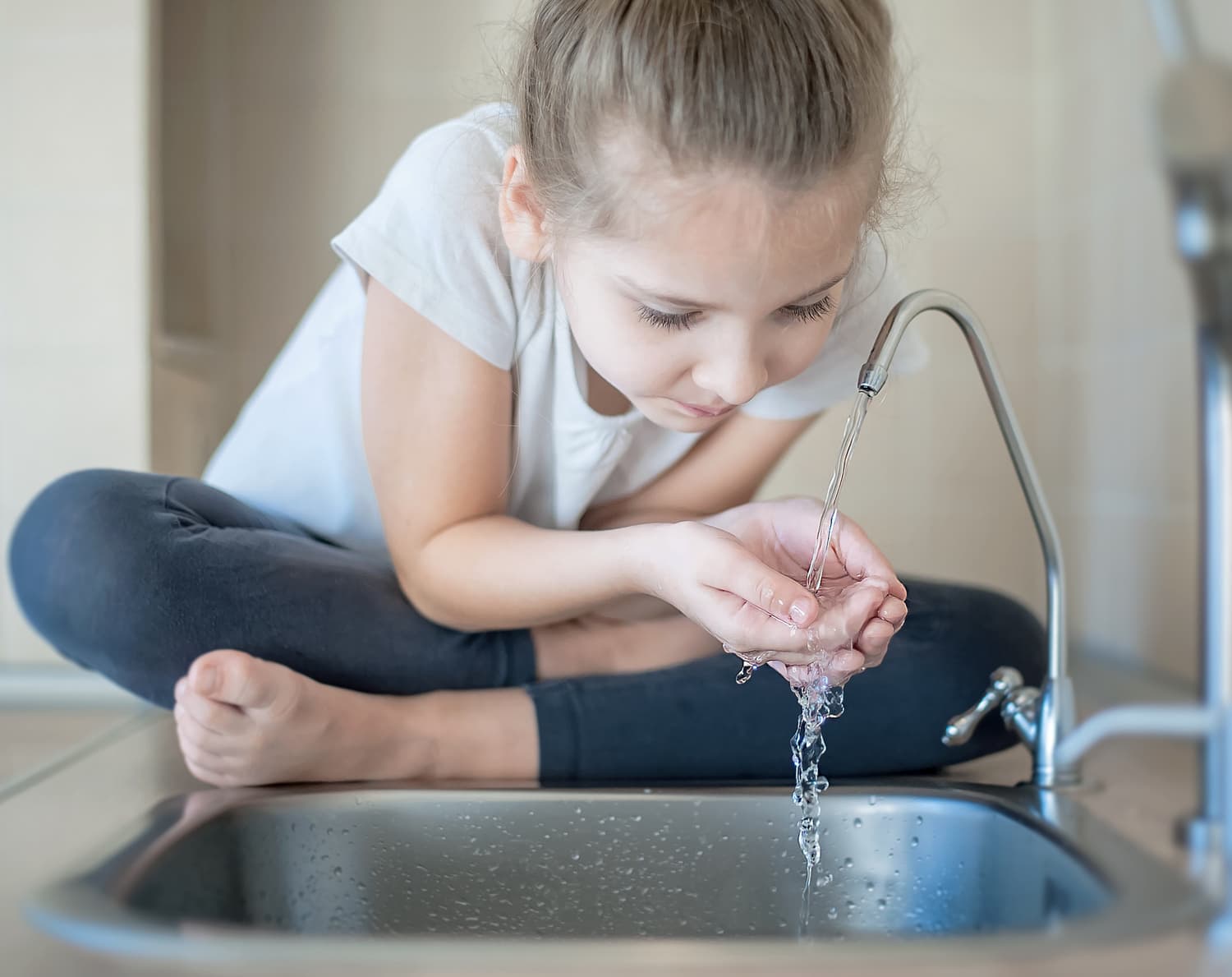 little girl drinking fresh water in kitchen at home. T