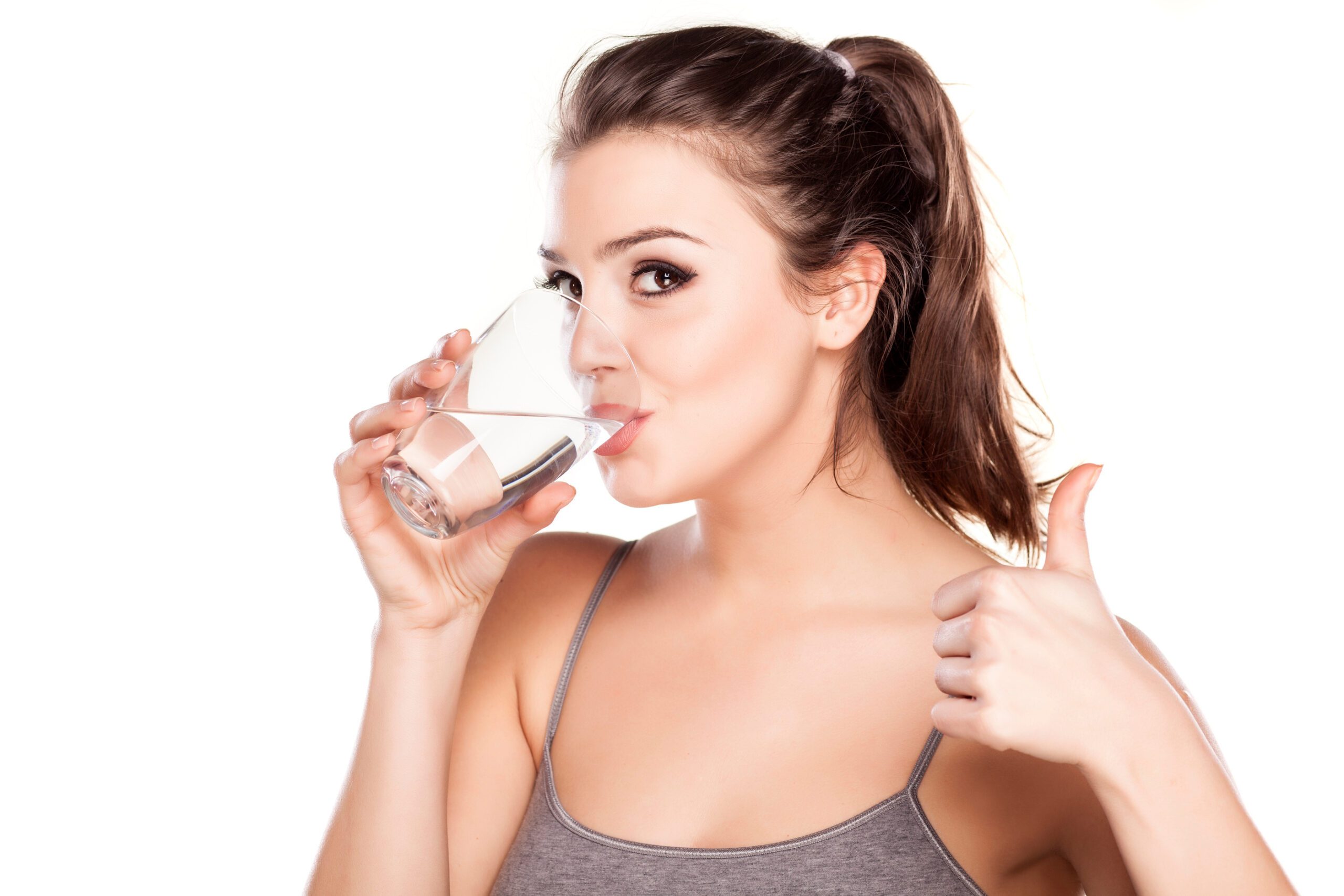 beautiful woman drinking water from a glass and showing thumbs up