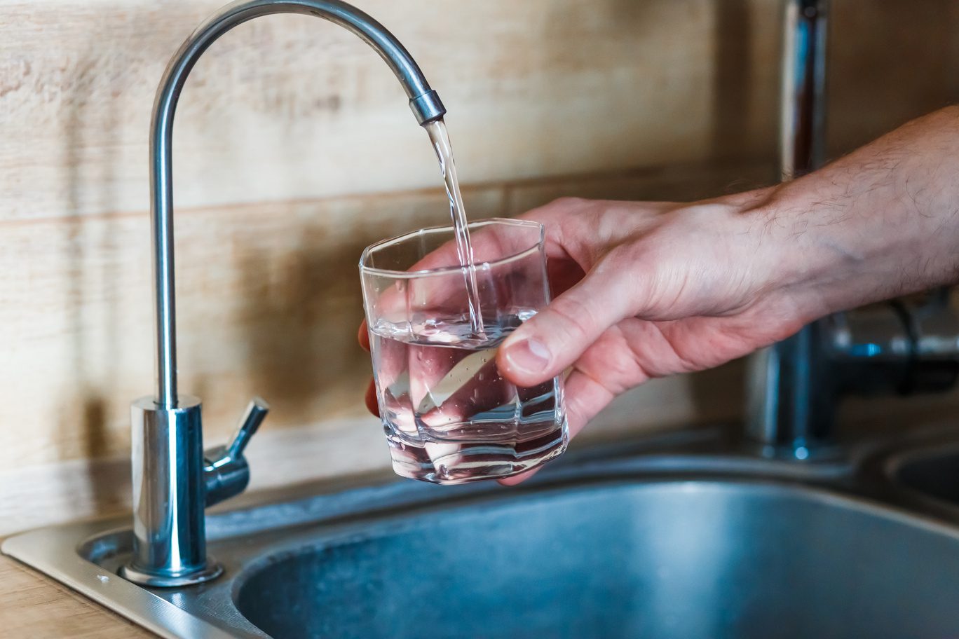 hand holding a glass of water. a man pouring water from tap