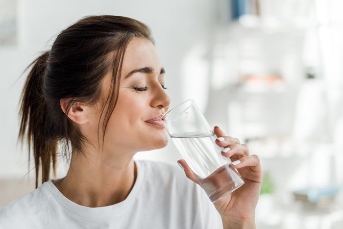smiling girl holding drinking water from glass