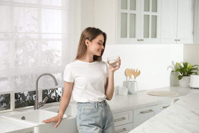 Woman drinking water from glass in kitchen