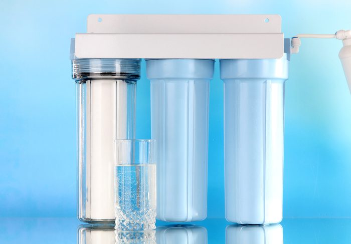 Filter system for water treatment with glass on blue background