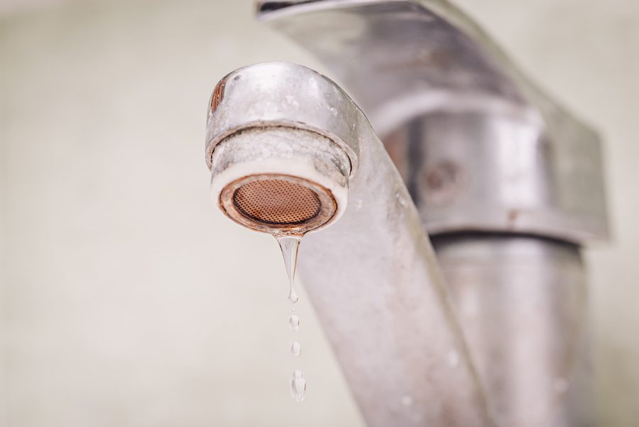 Water dripping from tap covered in limestone because of hard water