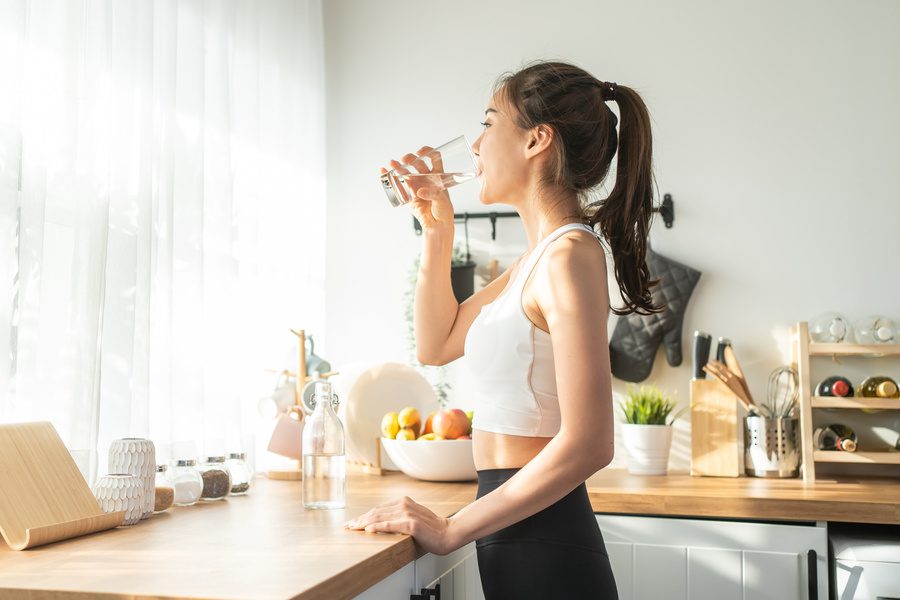 woman in sportswear drink water after exercise at home
