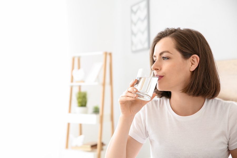 young woman drinking chlorine free filtered drinking water in a glass